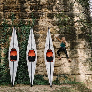 woman climbing wall with Oru Kayaks leaning against it