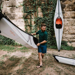 man carrying an Oru Kayak Bay ST down to the river