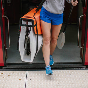 woman exiting train carrying an Oru Kayak Bay ST folded box
