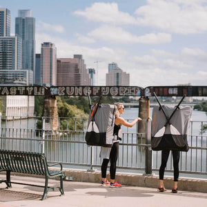 two women with Oru Kayak backpacks looking over bridge